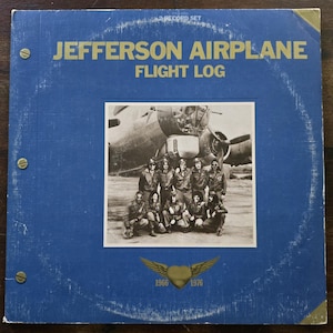 May include: A vintage vinyl record album cover for "Jefferson Airplane Flight Log." The cover is blue with gold lettering and features a black and white photo of the band in front of an airplane. The album's release years, 1966 and 1976, are also displayed.