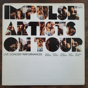 Może przedstawiać: Vintage okładka albumu winylowego dla "Impulse Artists On Tour". Okładka zawiera tytuł albumu dużymi, pogrubionymi literami z kolażem zdjęć. Nazwiska artystów są wymienione pod tytułem.