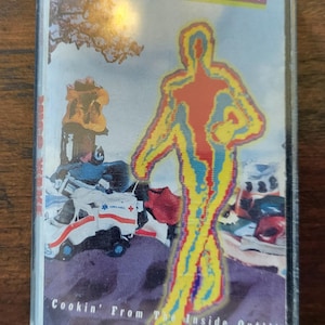May include: A vintage cassette tape with the title "Mico Wave" in a red and yellow font. The cover art features a colorful human figure and an ambulance. The text "Cookin' From The Inside Out!!!" is also visible.