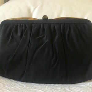 May include: A black satin clutch purse with a gold metal clasp.