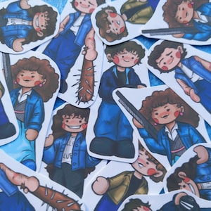 May include: A selection of stickers depicting a cartoon character in a blue jacket, blue trousers, and a white shirt. Some stickers show the character holding a spiked bat or a rifle. The stickers have a white border and are scattered on a blue surface.