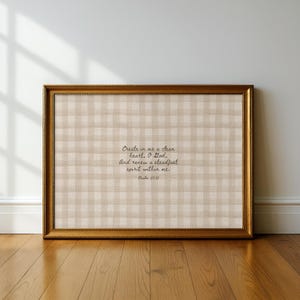 May include: A framed artwork with a gold-colored frame. The artwork features a beige and white checkered pattern background with the text "Create in me a clean heart, O God, And renew a steadfast spirit within me. Psalm 51:11" in black script.