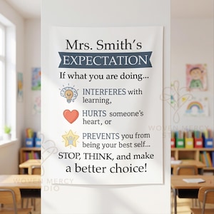 May include: A white wall hanging featuring the text Mrs. Smith's EXPECTATION. It lists three rules with icons: a lightbulb for learning, a red heart for hurting others, and a yellow star for being your best self, ending with STOP, THINK, and make a better choice!