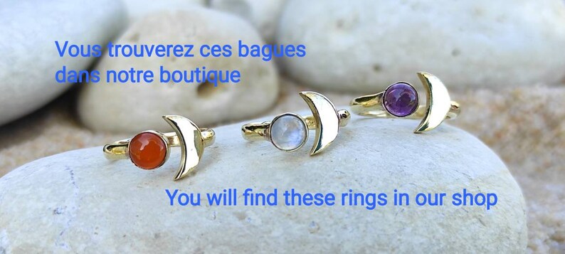 May include: Four gold crescent moon rings with different colored gemstones. The rings feature a crescent moon design with a gemstone set in the center. The gemstones are orange, white, purple, and a light blue color.