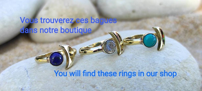 May include: Three gold rings with crescent moon designs. Each ring features a different gemstone: a blue lapis lazuli, a grey labradorite, and a turquoise stone.