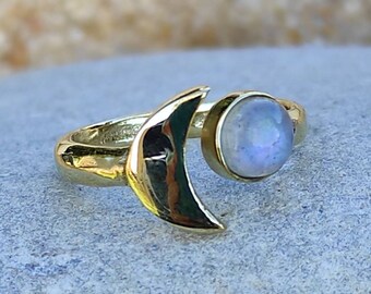 May include: A gold ring with a crescent moon design and a round moonstone gemstone.