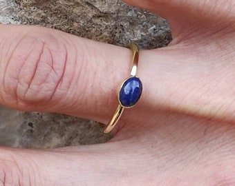 Può includere: Un anello d'oro con una pietra ovale blu.