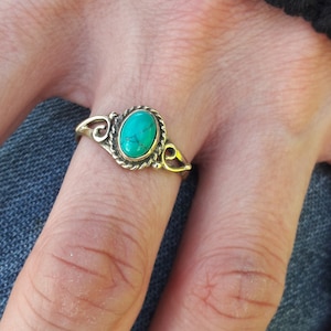 Peut inclure: Une bague en argent avec une pierre turquoise sertie dans un cadre ovale décoratif.