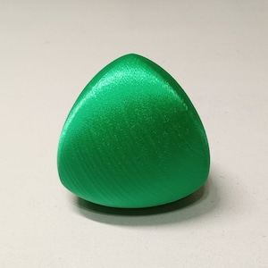 Puede incluir: Un objeto de forma triangular, liso y de color verde brillante. Está hecho de un material que parece ser plástico o resina.