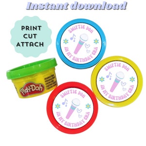 May include: Three colourful Play-Doh containers with custom labels that say "Swiftie Doh in my birthday era". The labels feature a pink microphone, musical notes, and hearts.