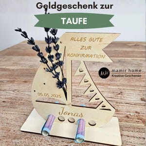 K&ouml;nnte beinhalten: Ein h&ouml;lzerner Geschenkhalter in Segelbootform mit dem Text "ALLES GUTE ZUR KONFIRMATION" und dem Namen "Jonas". Es zeigt das Datum 05.05.2025 und h&auml;lt aufgerollte Geldscheine. Das Design umfasst Ausschnitte und einen Lavendelzweig.