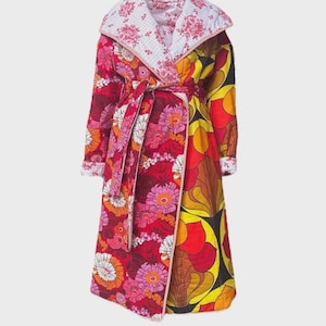 May include: A long, quilted robe with a vibrant floral pattern in red, pink, orange, and yellow. The robe features a white floral collar and cuffs, and a matching belt. The design is reminiscent of vintage styles.