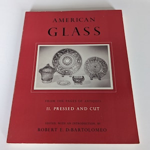 May include: A red book titled "American Glass" with the subtitle "From the Pages of Antiques II. Pressed and Cut" and an image of pressed glass plates and bowls on the cover. Edited with an introduction by Robert E. DiBartolomeo.