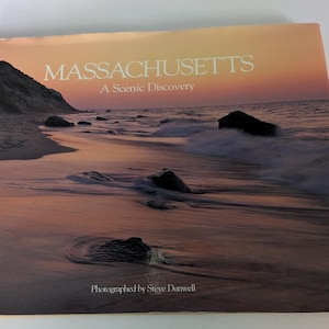 Peut inclure: Couverture de livre avec une plage pittoresque au coucher du soleil. Le titre "MASSACHUSETTS" est en blanc, avec "A Scenic Discovery" en dessous. La photographie est créditée à Steve Dunwell.