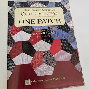 May include: Open book titled "The Classic American Quilt Collection: One Patch." The cover features a patchwork design with various fabric patterns in red, black, blue, and white. The book is edited by Karen Costello Soltys and published by Rodale Press.