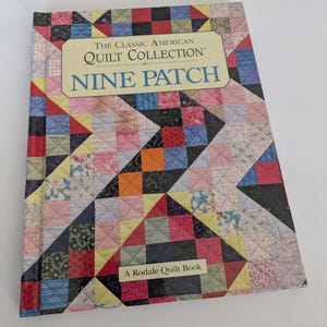 May include: A book titled "The Classic American Quilt Collection Nine Patch" with a colorful patchwork quilt design on the cover. The cover features a variety of fabric patterns in red, blue, yellow, and green.