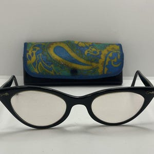 May include: Black cat-eye glasses with clear lenses and a paisley patterned case.