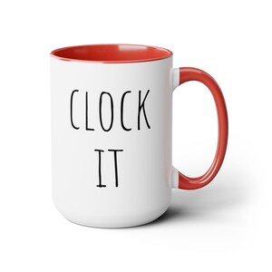 May include: White ceramic mug with a red interior and handle. The mug features the words "CLOCK IT" in black, handwritten-style lettering. A simple, yet bold design for coffee, tea, or any favorite beverage.