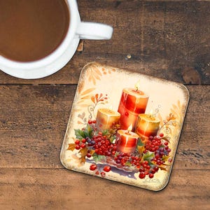 May include: A square coaster with a vintage-inspired design featuring four candles surrounded by red berries and green leaves. The candles are red, yellow, and orange with flames.