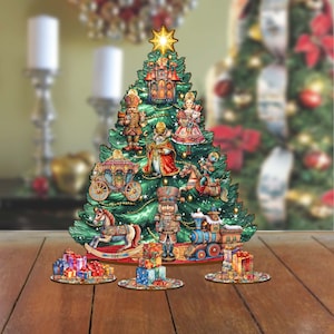 May include: A wooden Christmas tree ornament with a green tree and a variety of colorful ornaments, including a nutcracker, a rocking horse, a carriage, and a train. The ornaments are arranged around the base of the tree, which is decorated with a red and gold ribbon.