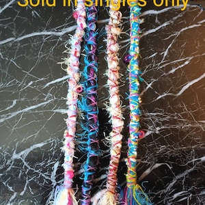 May include: Four colorful crocheted hair extensions with beads and fringe. The text "Sold in singles only" is visible in the image.