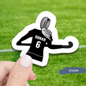 Puede incluir: Pegatina en blanco y negro de una jugadora de hockey sobre hierba con el nombre "Bonar" y el número "6" en la parte posterior de su camiseta.