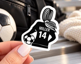 Puede incluir: Una pegatina troquelada que muestra la silueta negra de una jugadora de fútbol con coleta, vistiendo una camiseta con el nombre MILLER y el número 14 en blanco, mientras sostiene un balón de fútbol bajo el brazo.