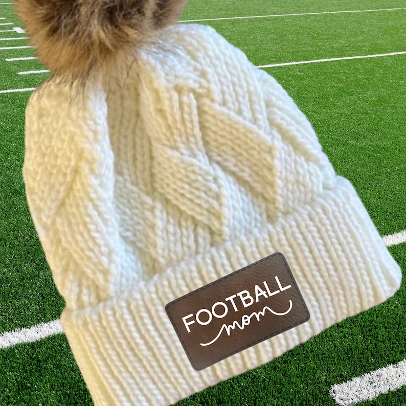 Football Mom Beanie Winter Hat Custom Leather Patch Design Cable Knit Construction Warm Winter Accessory Fur Pom Detail Sports Team Support Gear Player Name Number Personalization Cold Weather Essential Gray Knit Material Field Side Comfort