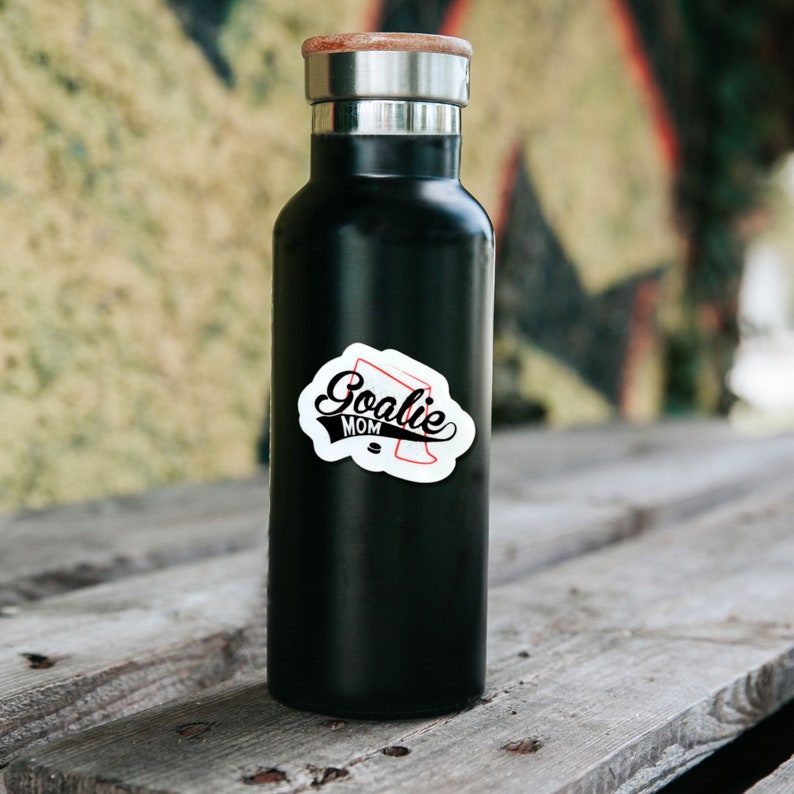 May include: Black water bottle with a white sticker that says "Goalie Mom" with a red hockey stick graphic.