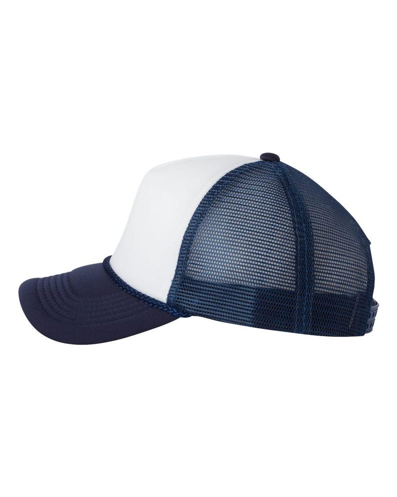 May include: A navy blue and white trucker hat. The hat features a white front panel, a navy blue brim, and a navy blue mesh back. A navy blue rope trim accents the front panel and brim. The hat has a curved brim and a snap closure.