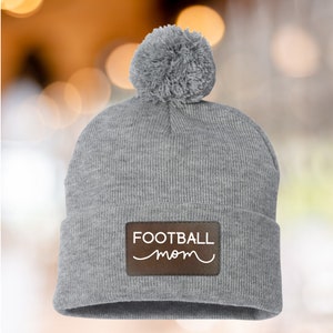 Football Mom Beanie Winter Hat Custom Leather Patch Design Cable Knit Construction Warm Winter Accessory Fur Pom Detail Sports Team Support Gear Player Name Number Personalization Cold Weather Essential Gray Knit Material Field Side Comfort