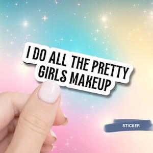 Puede incluir: Una pegatina blanca con el texto "I DO ALL THE PRETTY GIRLS MAKEUP" en letras negras en negrita. La pegatina está sujeta por una mano con esmalte de uñas rosa claro sobre un fondo colorido con estrellas.