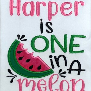 Op de afbeelding: Een witte romper met roze en groene borduursels. De romper zegt "Harper is one in a melon" met een watermeloenafbeelding.