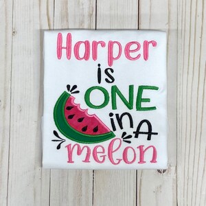 Op de afbeelding: Witte romper met roze en groene borduurwerk met de tekst "Harper is one in a melon" met een watermeloenafbeelding.