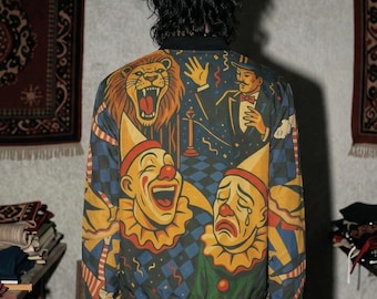 May include: A bomber jacket featuring a vibrant, multi-colored graphic print on the back. The design displays a roaring lion, a man in a tuxedo, and two clowns with contrasting expressions, one laughing and one crying, set against a blue checkered background.