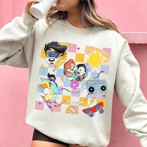 May include: A light gray sweatshirt featuring a colorful cartoon graphic. The graphic includes characters, a boombox, a skateboard, and the word "POWERLINE". The design is set against a checkered background with lightning bolts and stars.