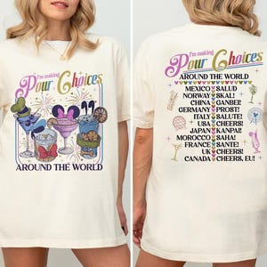 May include: Cream-colored t-shirt with a colorful graphic of cocktails and the text "I'm making Pour Choices Around the World." The back of the shirt lists countries and cheers in various languages.