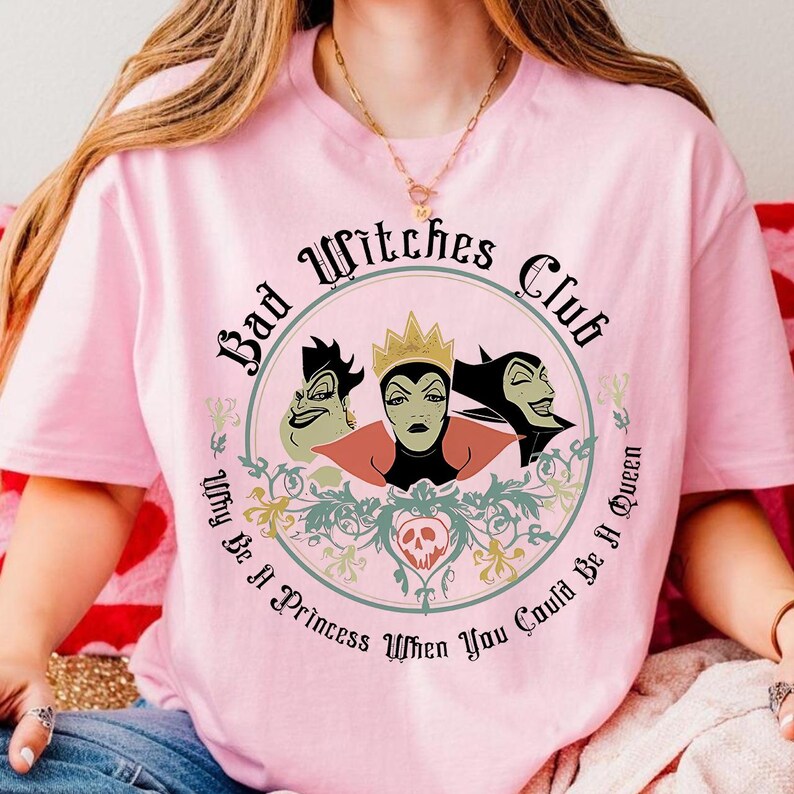 Peut inclure: T-shirt rose clair avec un motif circulaire repr&eacute;sentant trois personnages de sorci&egrave;res de dessins anim&eacute;s et le texte "Bad Witches Club". Le motif comprend la phrase "Why Be A Princess When You Could Be A Queen."