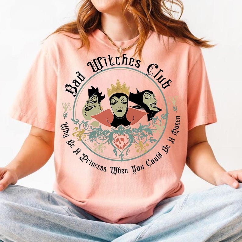Peut inclure: T-shirt p&ecirc;che avec un motif circulaire. Le motif comprend le texte "Bad Witches Club" et des illustrations de trois sorci&egrave;res de dessins anim&eacute;s. La phrase "Why Be A Princess When You Could Be A Queen" est &eacute;galement incluse.