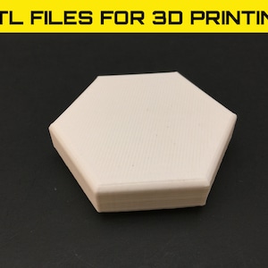May include: A white, 3D printed hexagonal shape. The shape has a smooth, slightly textured surface.