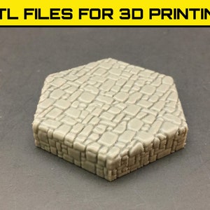 May include: A light grey, hexagonal 3D-printed tile with a textured, cobblestone-like surface. The tile is a solid colour and has a detailed, realistic appearance. The top of the image reads ".STL FILES FOR 3D PRINTING."
