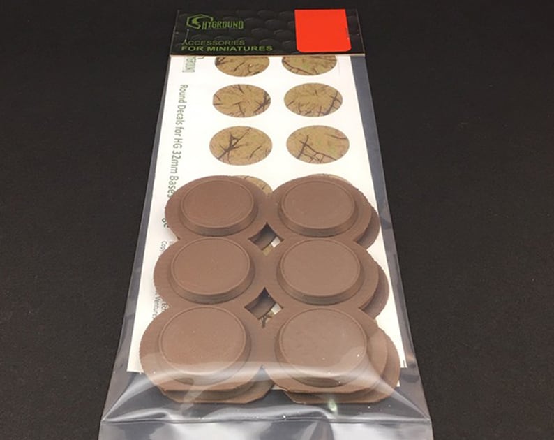 May include: A package of miniature accessories. The package contains brown round bases and oval decals with a textured, tan and brown pattern. The packaging includes the text "ACCESSORIES FOR MINIATURES".