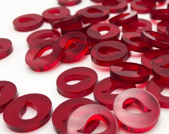 May include: A large group of red plastic tokens with a teardrop-shaped cutout in the center. The tokens are scattered on a white surface.