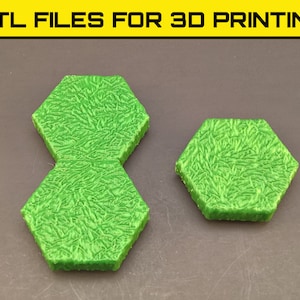 Puede incluir: Dos baldosas hexagonales de color verde impresas en 3D con una superficie texturizada. Las baldosas están diseñadas para parecer césped.