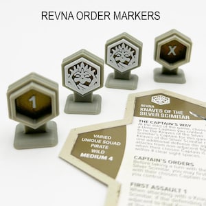 Könnte beinhalten: Ein Satz von vier grauen Plastik-Spielmarken für ein Brettspiel. Die Spielmarken zeigen verschiedene Symbole, darunter eine Zahl "1", ein "X" und zwei identische Bilder einer Kreatur mit einer Krone. Die Spielmarken befinden sich auf einem Tisch neben einer Karte mit dem Text "REVNA KNAVES OF THE SILVER SCIMITAR" und Spielanweisungen.