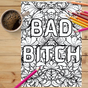 May include: A black and white adult coloring page with the words "BAD BITCH" in large block letters. The page is surrounded by a detailed floral design. Colored pencils and a cup of coffee are on the wooden surface.