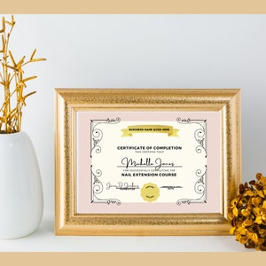 May include: A pink and gold certificate of completion for a nail extension course. The certificate is framed in a gold frame and has a decorative border. The text on the certificate reads "BUSINESS NAME GOES HERE", "CERTIFICATE OF COMPLETION", "THIS CERTIFIES THAT", "Michelle Jones", "FOR SUCCESSFULLY COMPLETING THE", "NAIL EXTENSION COURSE", "Jennie Jenkins", "INSTRUCTOR", and "DATE".