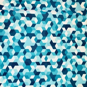 May include: A blue and white geometric pattern fabric with a repeating design of cubes. The fabric has a subtle sheen and a smooth texture.