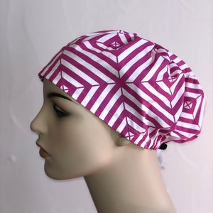 May include: A pink and white striped surgical scrub hat with a geometric pattern. The hat has a drawstring tie at the back.