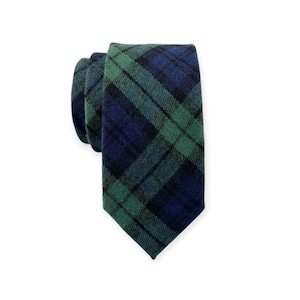 May include: A rolled-up necktie with a classic plaid pattern in shades of green and navy blue. The tie is made of a textured fabric and is displayed against a white background. The tie is a formal accessory.